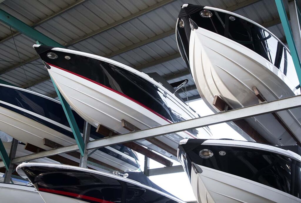 Rack of modern speedboats with pointed fiberglass hulls and bows, in a covered warehouse at a maritime storage dockyard